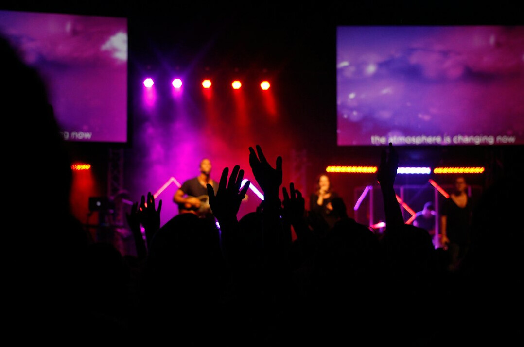 Concert stage with colorful lights and crowd hands in the air